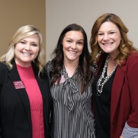 Three women smiling together.