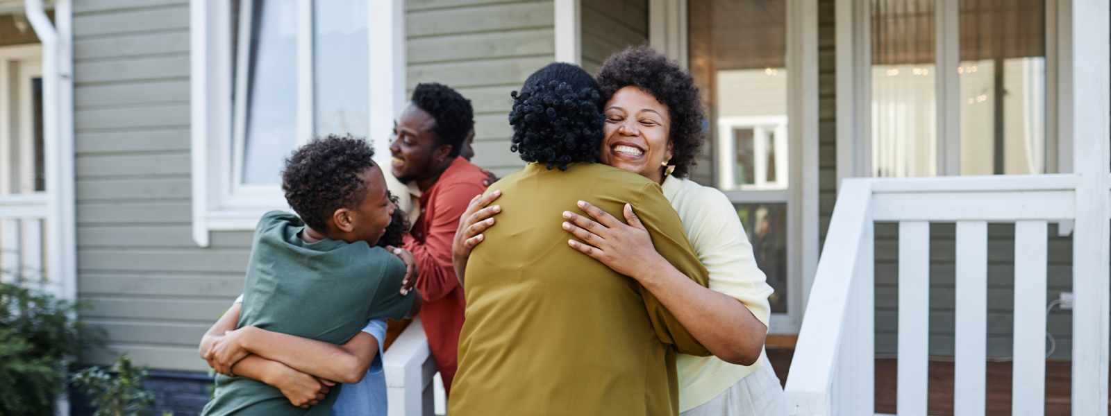 A group of people hugging outside a home.
