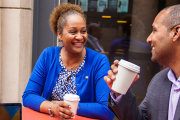 Two people sitting outside and drinking coffee.