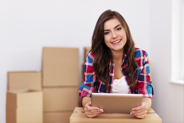 A girl holding an iPad with boxes behind her.