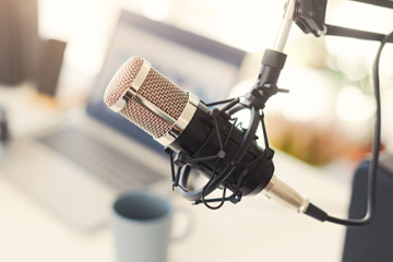 A microphone with a laptop on a desk in the background.