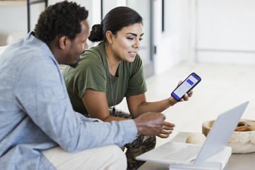 A man and a women sitting on a couch looking at a laptop.